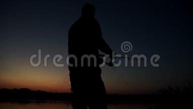 剪影渔夫在背景黄昏的日落中钓鱼